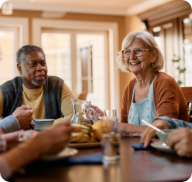 A senior couple smile as they share breakfast with friends. 